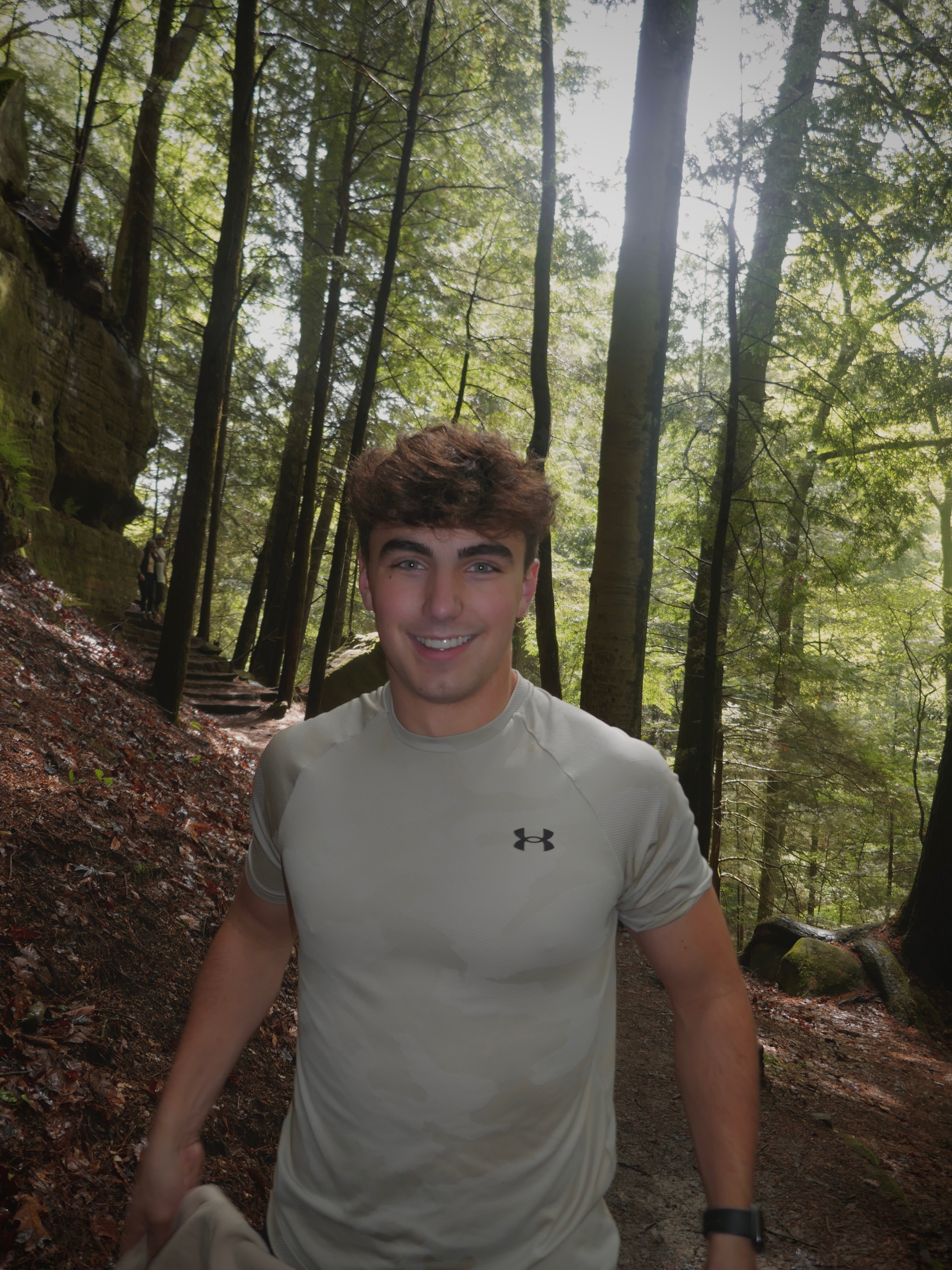 Jacob Tartabini hiking in the forest, surrounded by tall trees